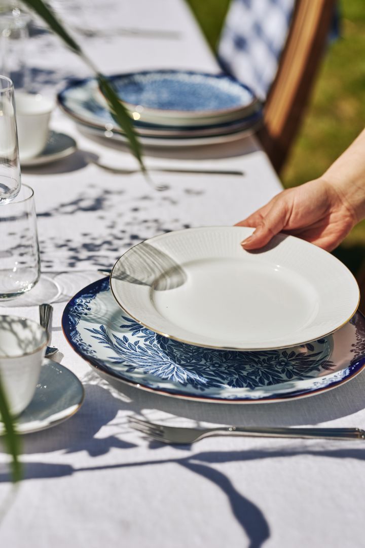 En tradisjonell borddekking til svensk midtsommer i blått og hvitt med Swedish Grace Gala-tallerken med gullomriss.