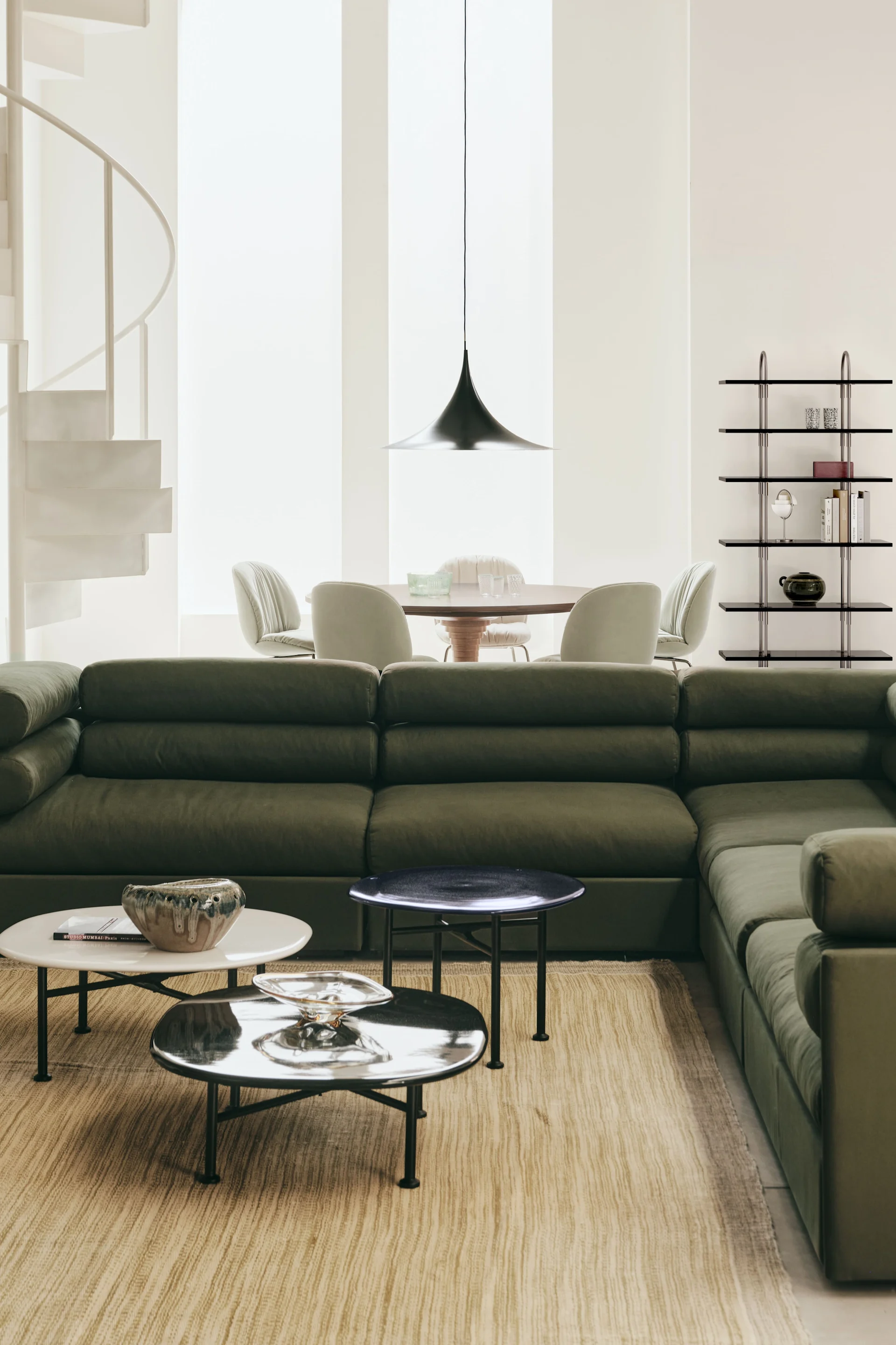 Den rette taklampen til stuen: Her henger Semi-pendellampen fra Gubi i en stue innredet med grønne møbler.
