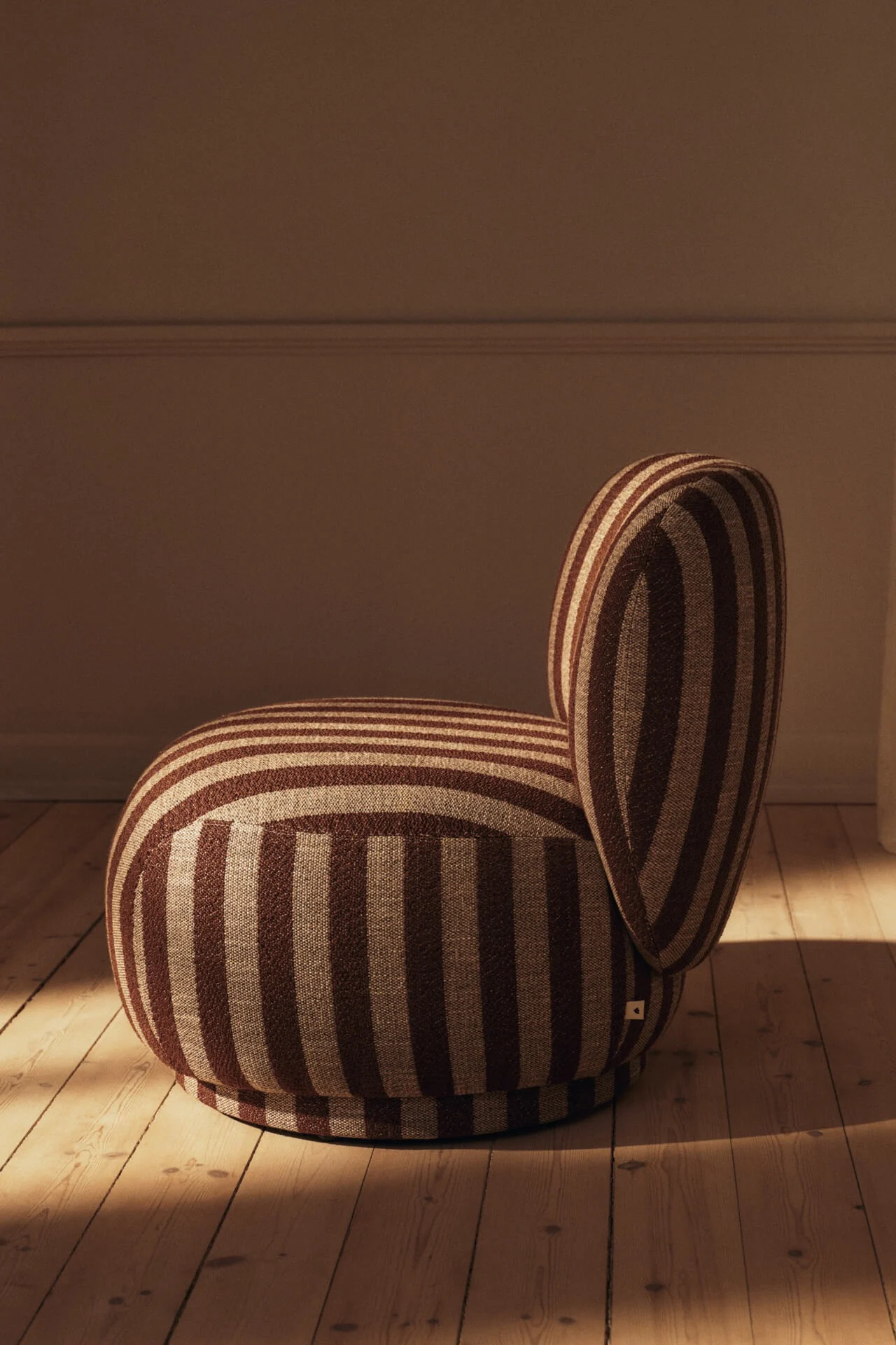 Rund lenestol med brune og beige striper på et tregulv.