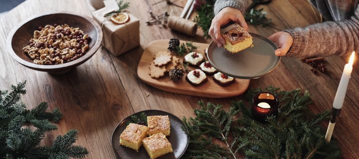 Adventsmys med julekaker, som myk pepperkake og safrankake på et bord med granbar og levende lys.