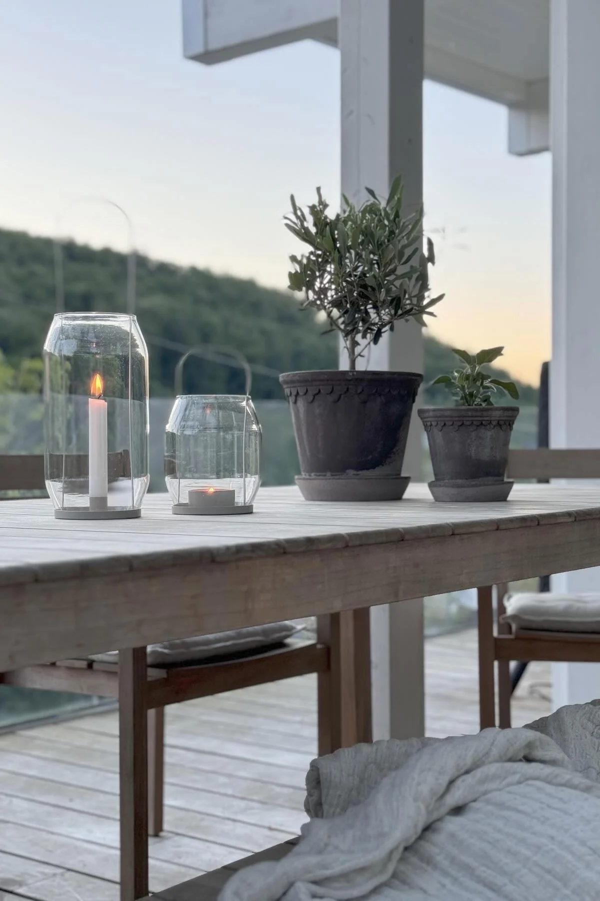 To grå Copenhagen blomsterpotter står på et bord ved siden av to Ernst-lykter i forskjellige størrelser på terrassen til @zuhauselig.