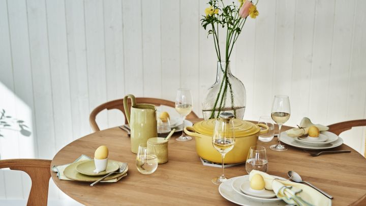 En stilig gul påskeduk med hvitt servise, men gule aksenter i form av servietter, egg og servise.