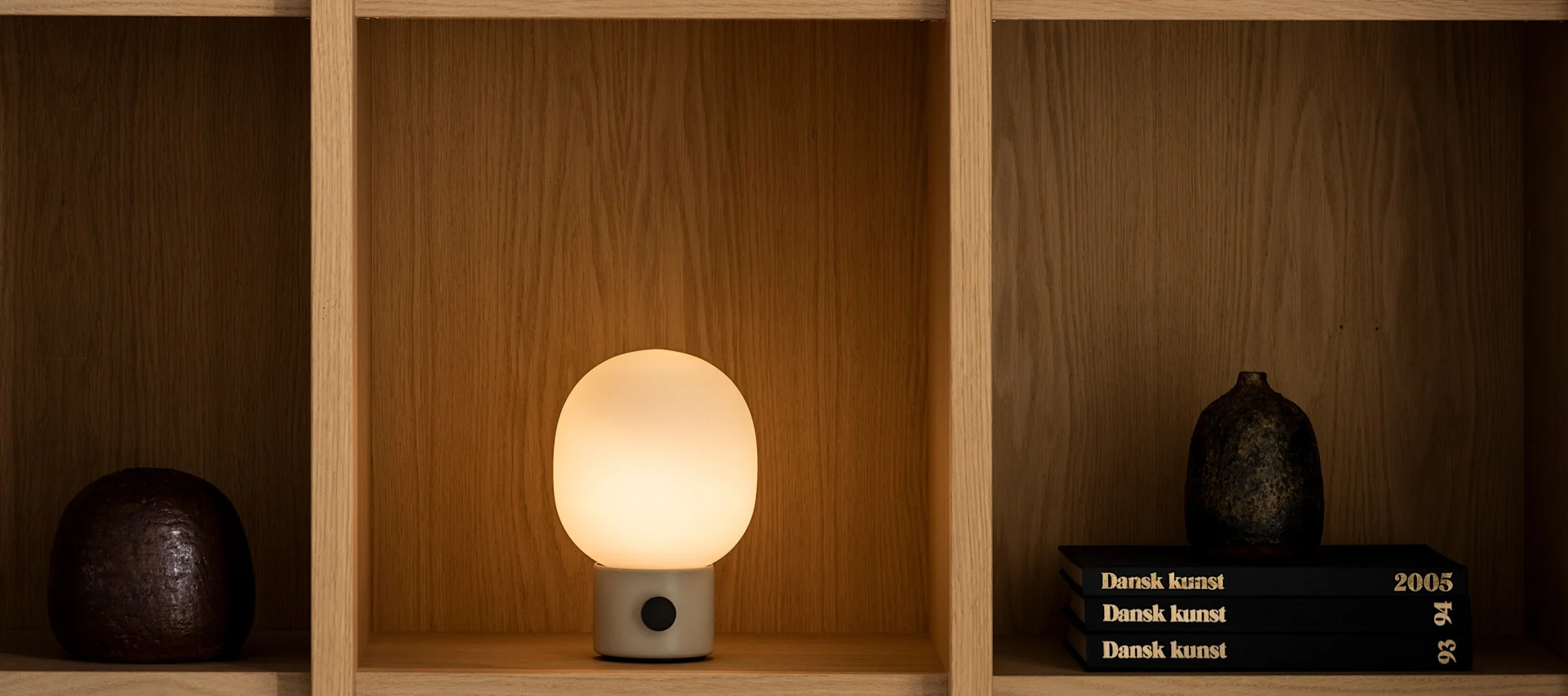 I stuen hos Audo Copenhagen: JWDA-bordlampe, svart hylle og vaser.