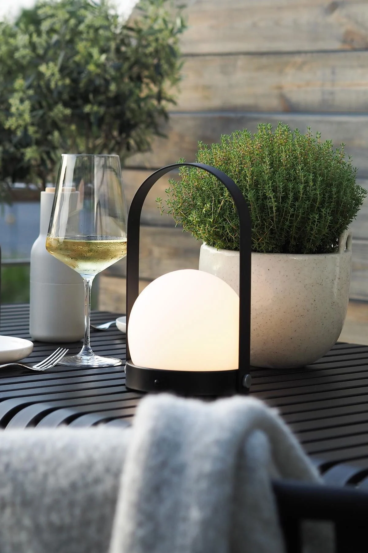 Den bærbare Carrie-lampen fra Audo Copenhagen og Speckle blomsterpotte fra Ferm Living står på Palissade-bordet fra HAY på @wohngluecksiebens terrasse.