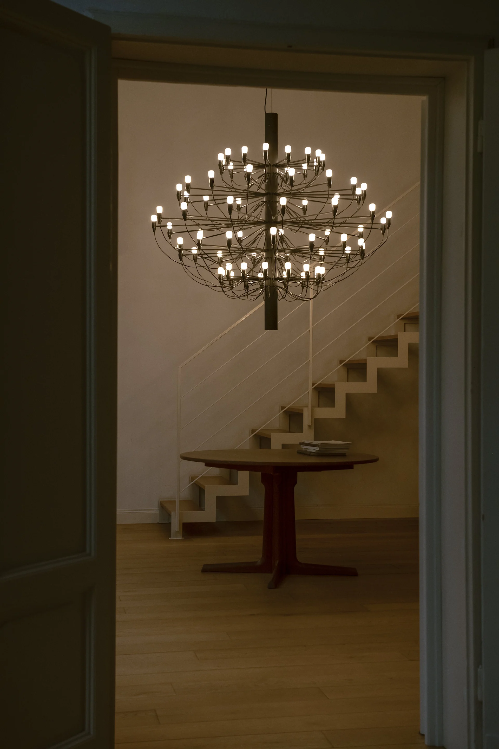 En svart Sarfatti taklampe henger foran en trapp. Lampen er en klassisk designlampe.
