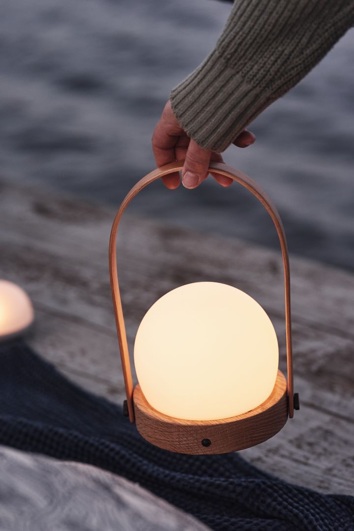 Her ser du den skandinaviske designlampen Carrie fra Audo Copenhagen, her på en brygge ved sjøen.