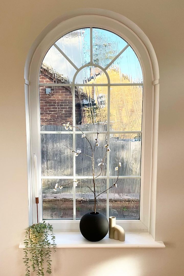 Her ser du det vakre buede vinduet med vinduskarm av @abrysonhouse, som er dekorert med lysestaker og den svarte kulevasen fra Cooee Design med vårblomster.