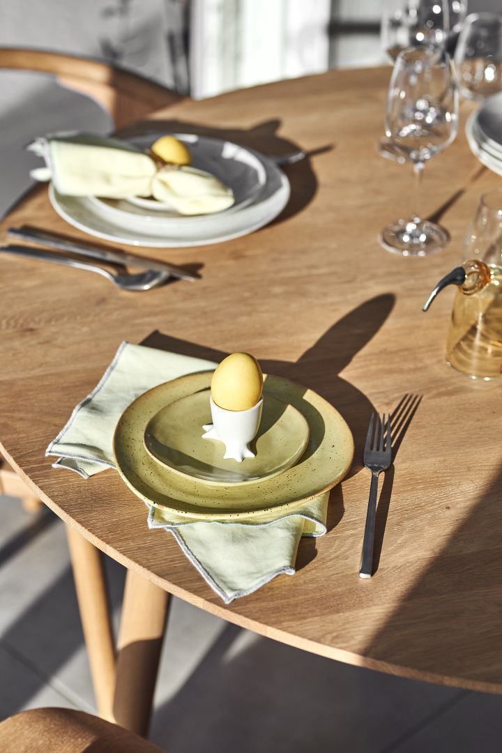 Et gult påskebord med gult servise og detaljer som servietter, egg og porselen i sitrongult og blekgult.