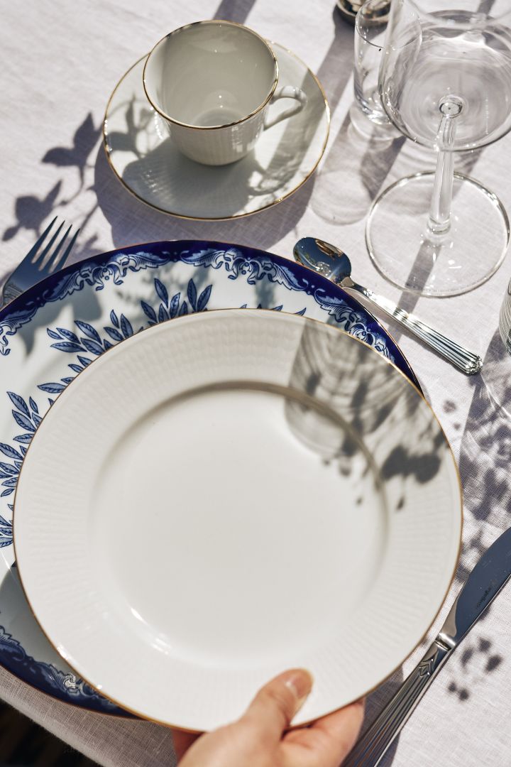 En vakker borddekking i blåttt og hvitt med høye stearinlys og blå fargeinnslag med hjelp av serviset Havsspil fra Scandi Living.