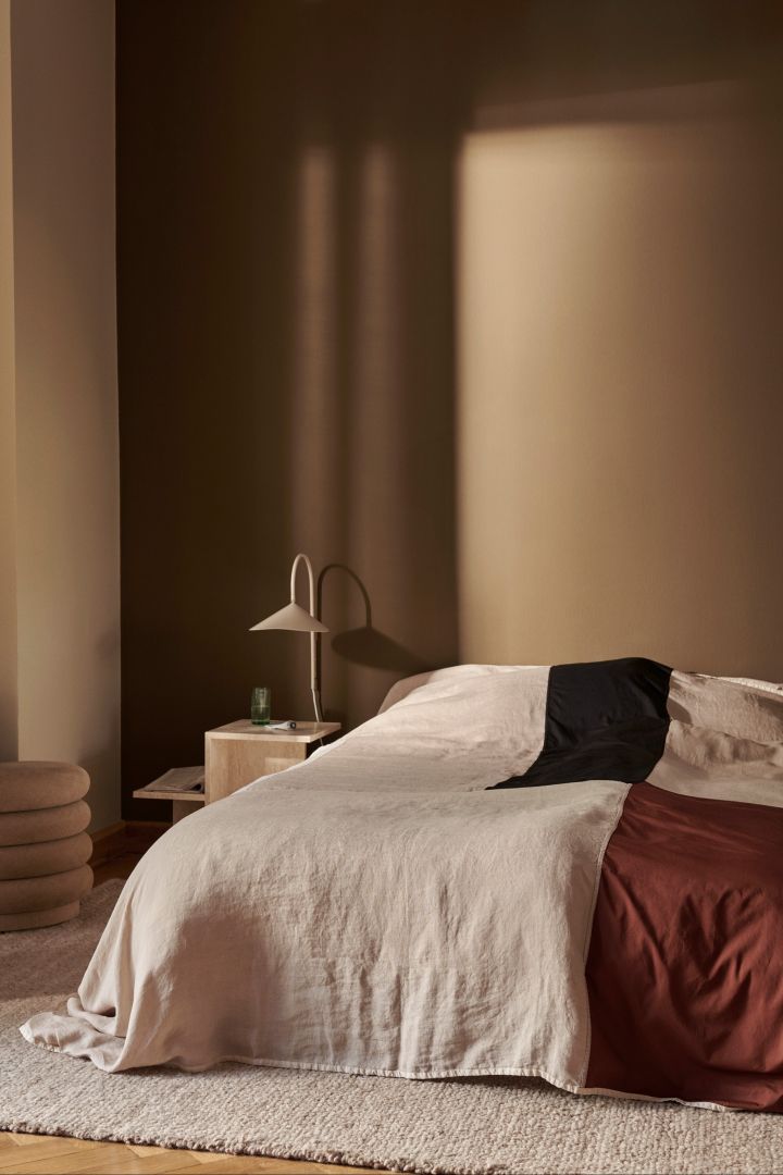 Arum vegglampe fra Ferm Living, her i soverom med brune vegger og lyst teppe, en vegglampe som passer perfekt som soveromslampe.