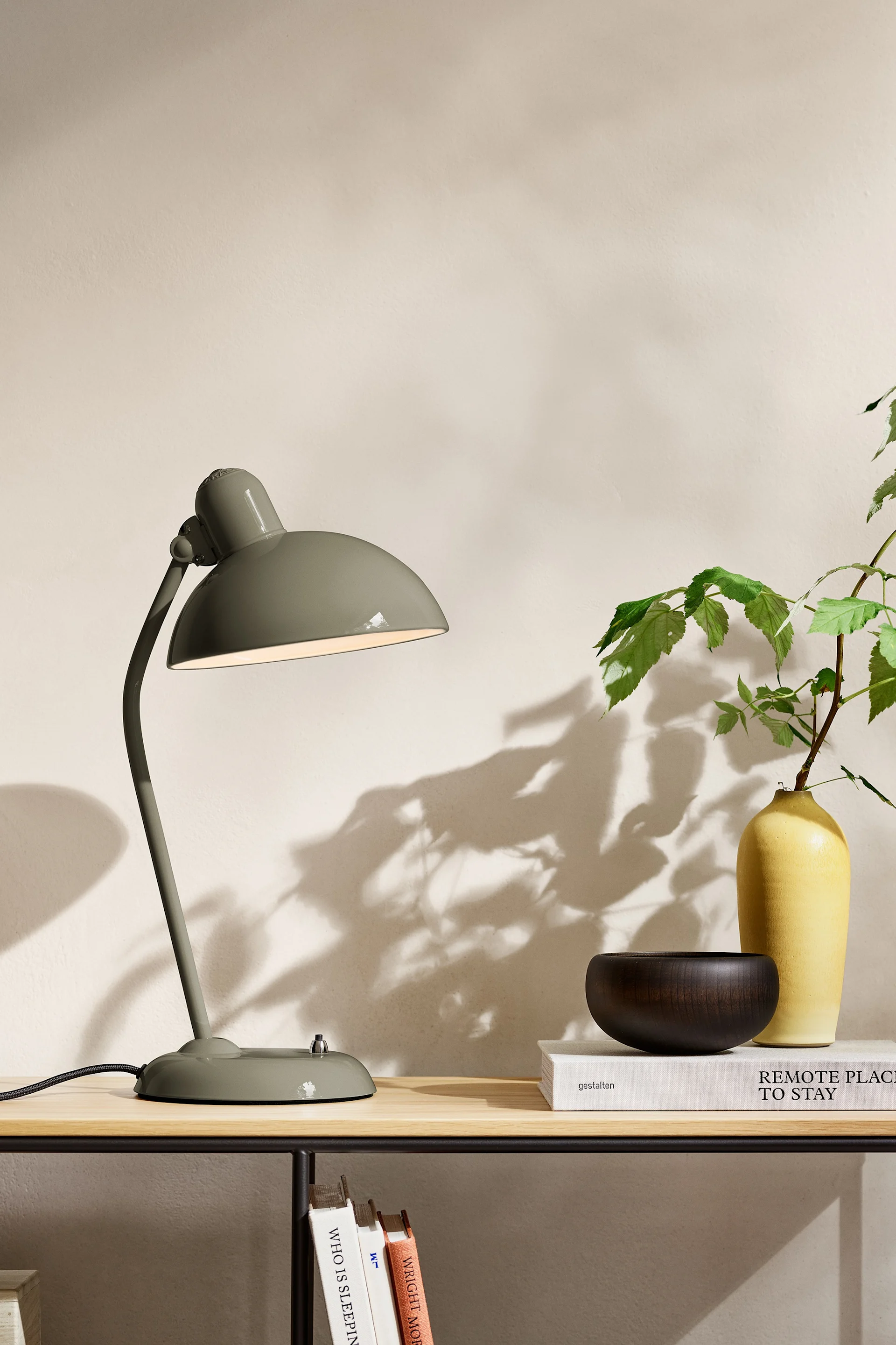 Blant fargetrender 2025 finner vi en naturlig nyanse av olivengrønn. Her ser du lampen fra Fritz Hansen plassert på et sidebord.