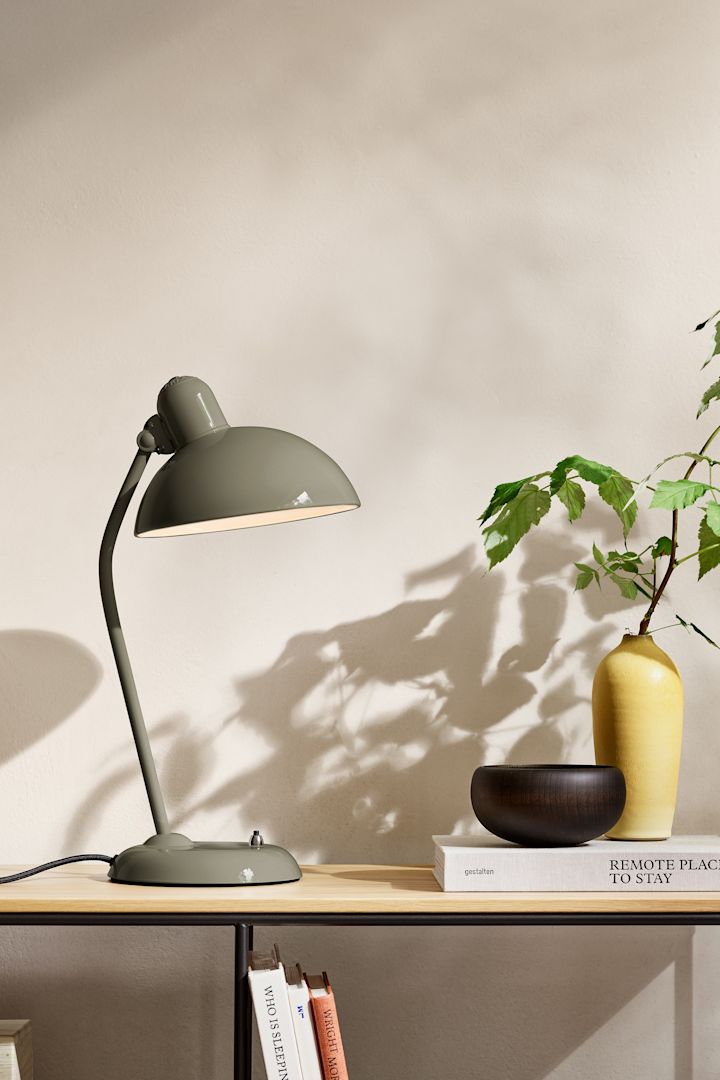 Blant fargetrender 2025 finner vi en naturlig nyanse av olivengrønn. Her ser du lampen fra Fritz Hansen plassert på et sidebord.