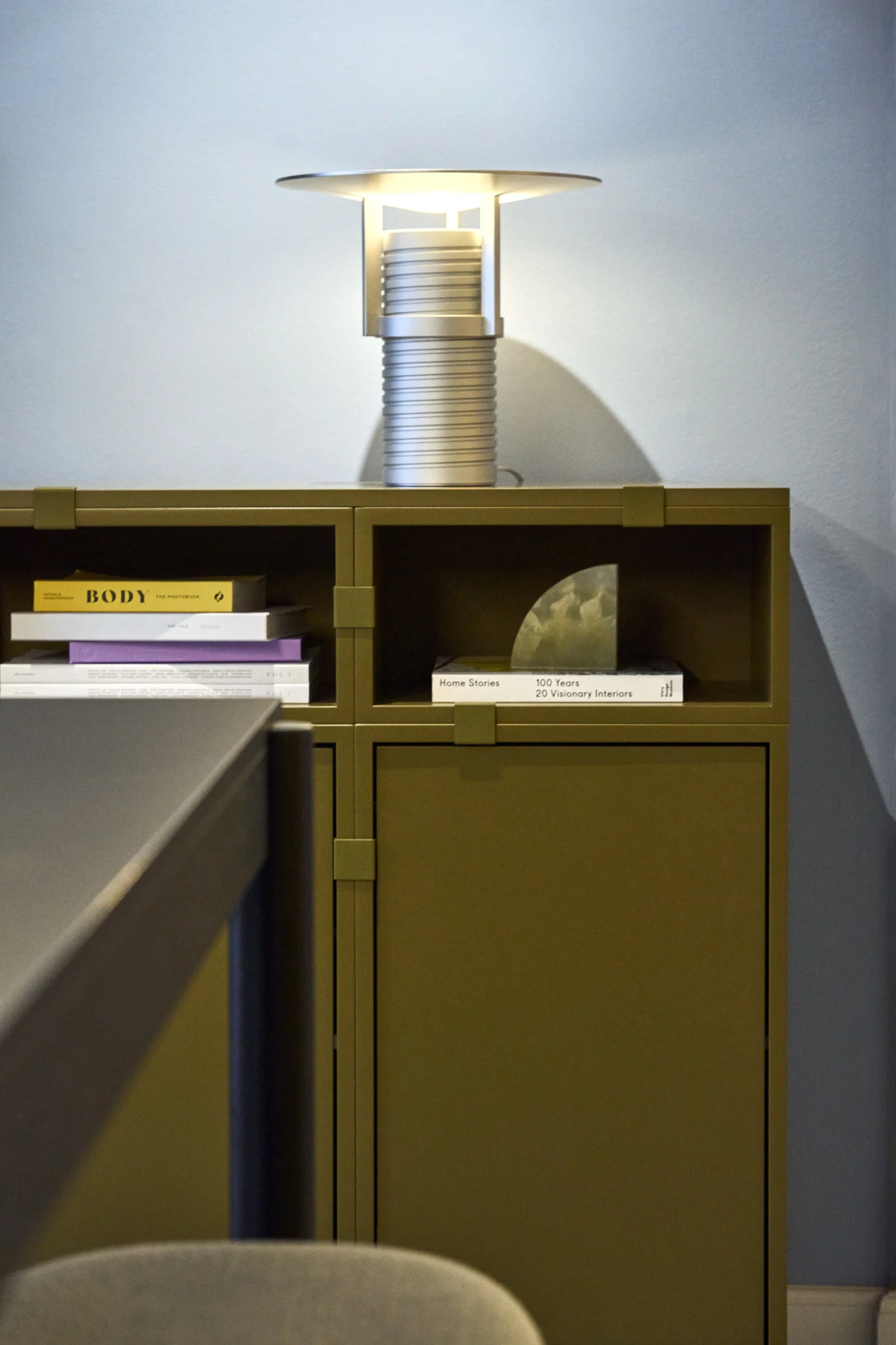 En grønn hylle bygget med moduler fra Stacked-kolleksjonen, med den sølvfargede Set-bordlampen på toppen – alt fra Muuto.