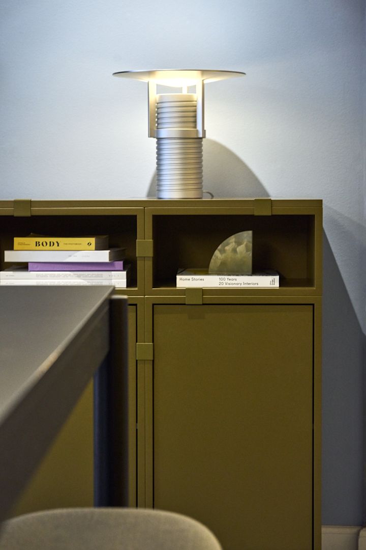 En grønn hylle bygget med moduler fra Stacked-kolleksjonen, med den sølvfargede Set-bordlampen på toppen – alt fra Muuto.