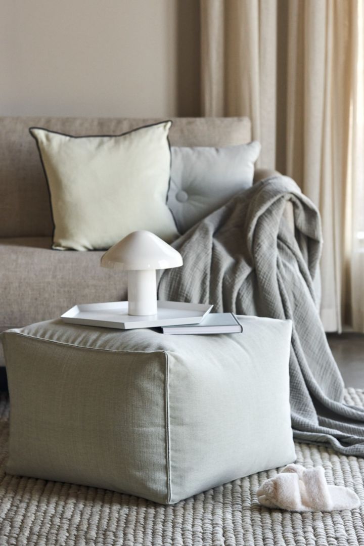 Bærbar og oppladbar lampe fra HAY i hvitt i en stilig, beige stue.