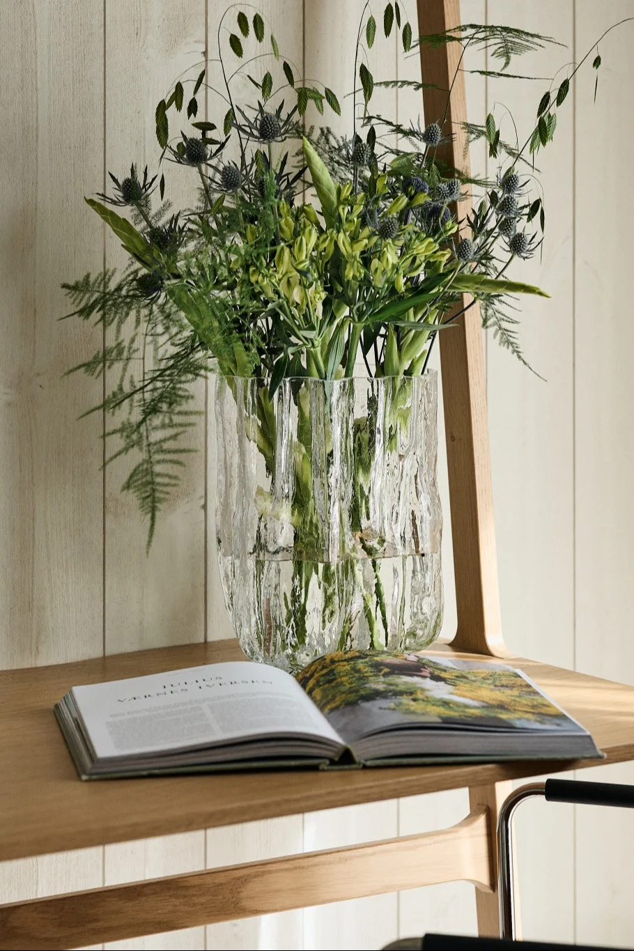 Den store Crackle-vasen fra Kosta Boda står på et skrivebord med en bukett tørkede blomster.