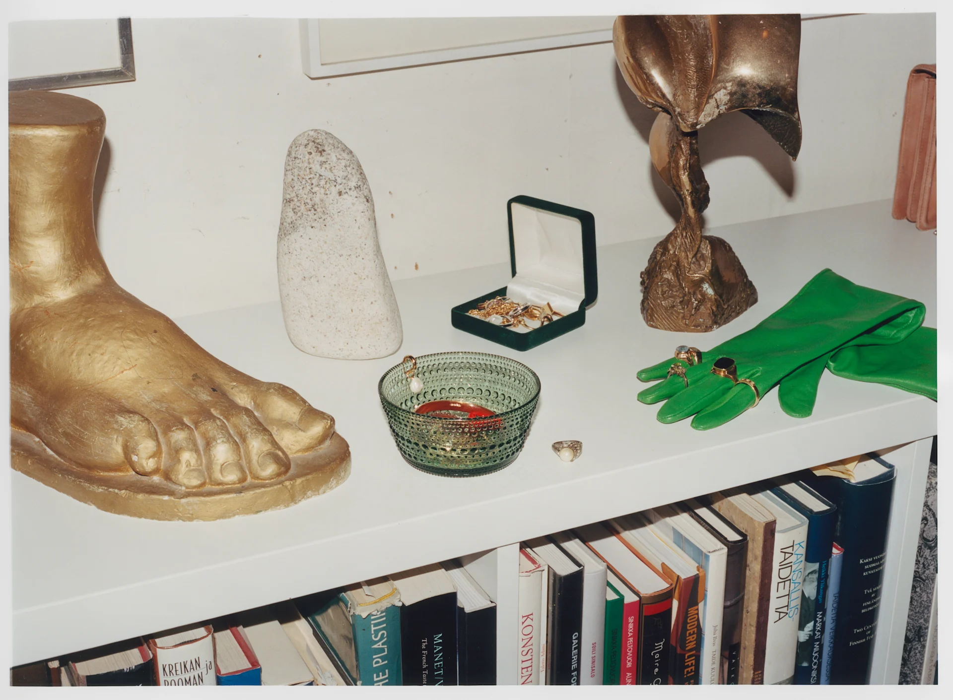 Iittala går inn i en ny æra men produktene er de samme, her Kastehelmi skål i grønt på en skjenk med statuer og hansker.