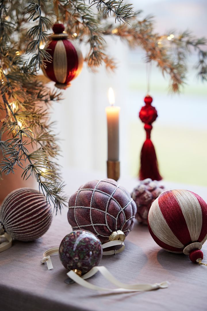 Flere julekuler fra Lene Bjerre ligger som julepynt på et bord.

