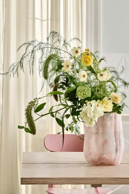 En rosa Crackle-vase fra Kosta Boda med blomster står på et bord, helt i tråd med fargetrender interiør 2026.
