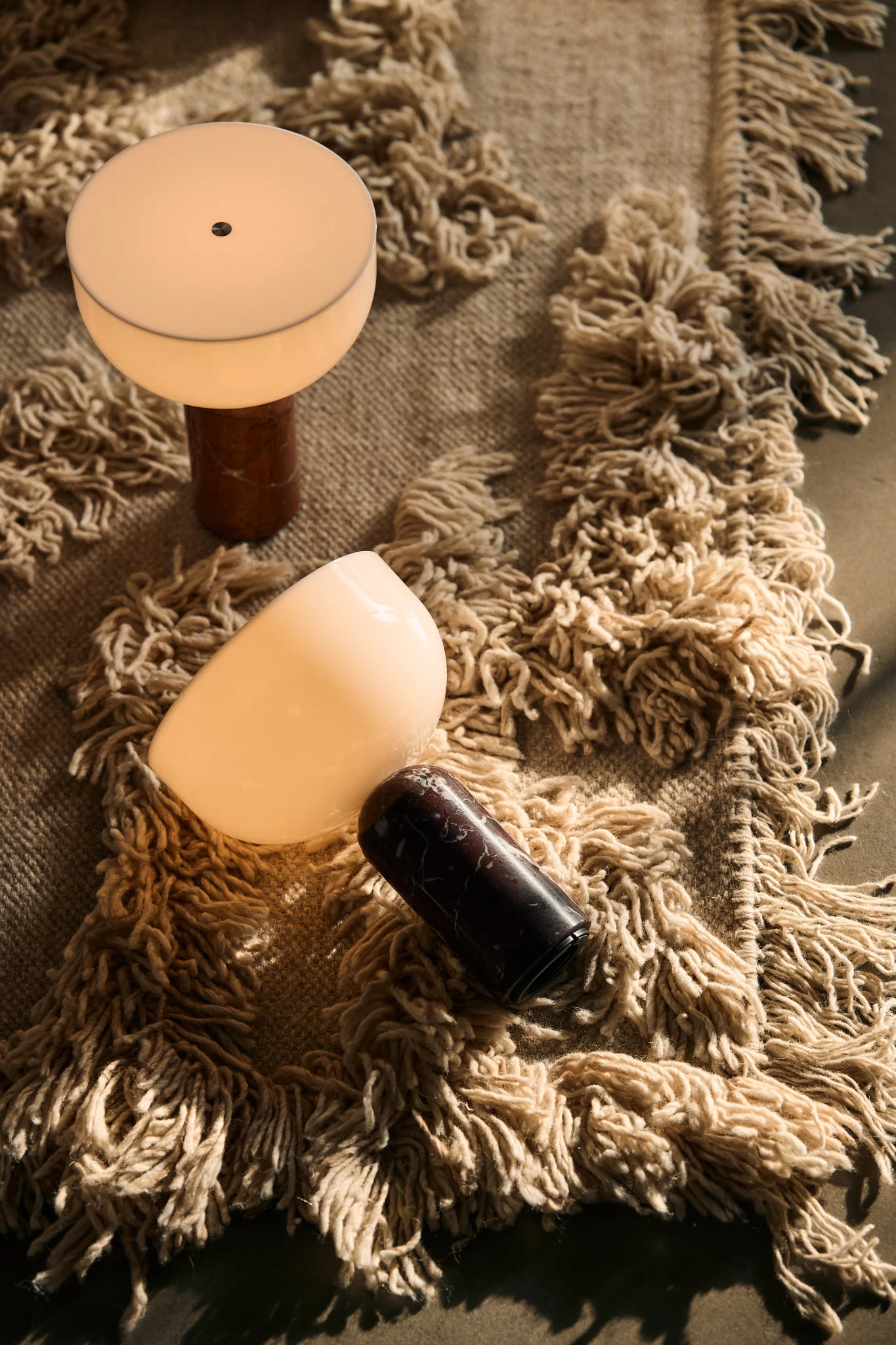 På et teppe ligger to Kizu-bordlamper fra New Works.
