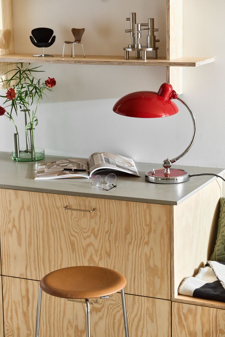 Kaiser Idell lampe i rødt, Ikaru vase og design fra Fritz Hansen i et stilrent, moderne kjøkken med kryssfiner. 