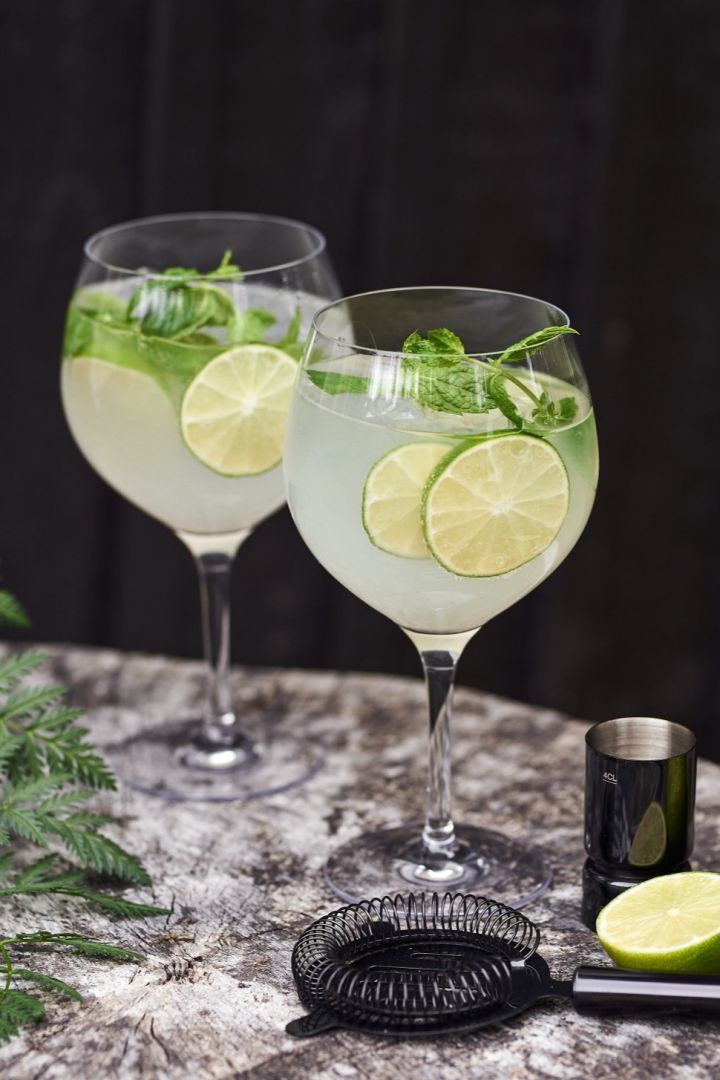 En gin og tonic type cocktailglass med cocktail og lime.