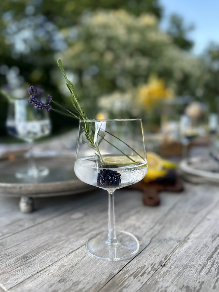 En gin og tonic type cocktailglass med cocktail og lime.