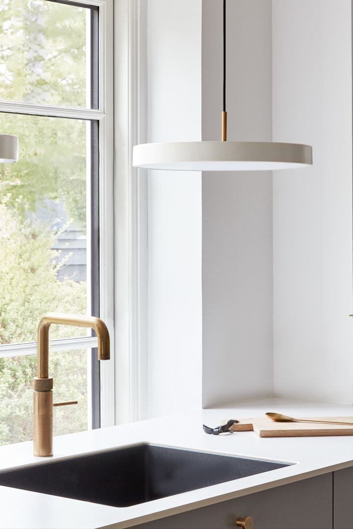 Bruk store pendellamper hvis du trenger litt mer lys på steder som vasken. Her ser du pendellampen Asteria Micro i perlehvit fra Umage hengende over en vask.