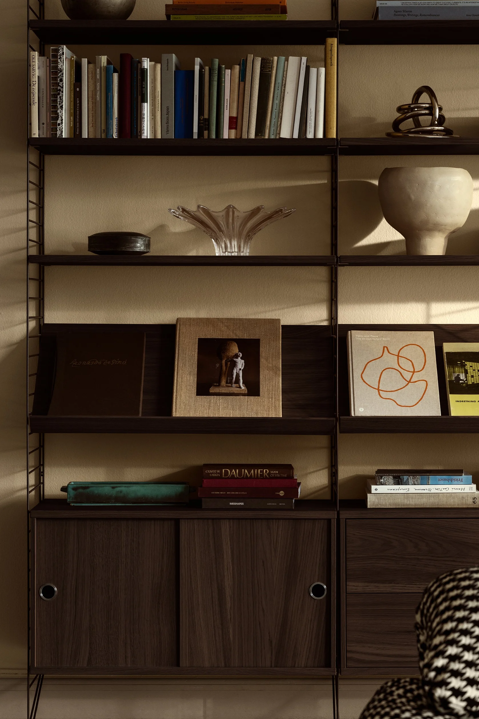 String hyllesystem passer perfekt som veggdekor. Her ser du hyllesystemet stylet med personlige detaljer som bøker og skåler.