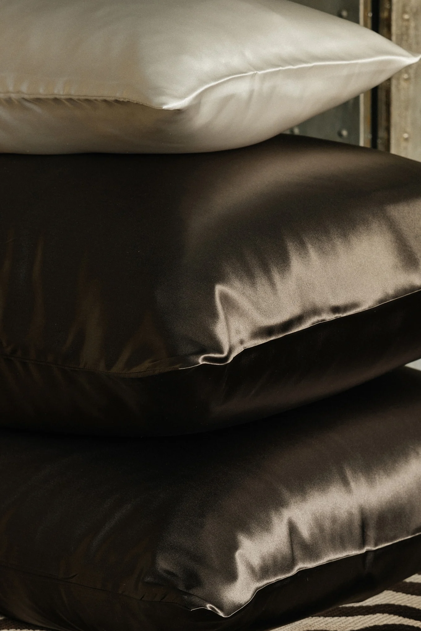 Stabel med tre silkeputer, en lys og to mørkebrune.