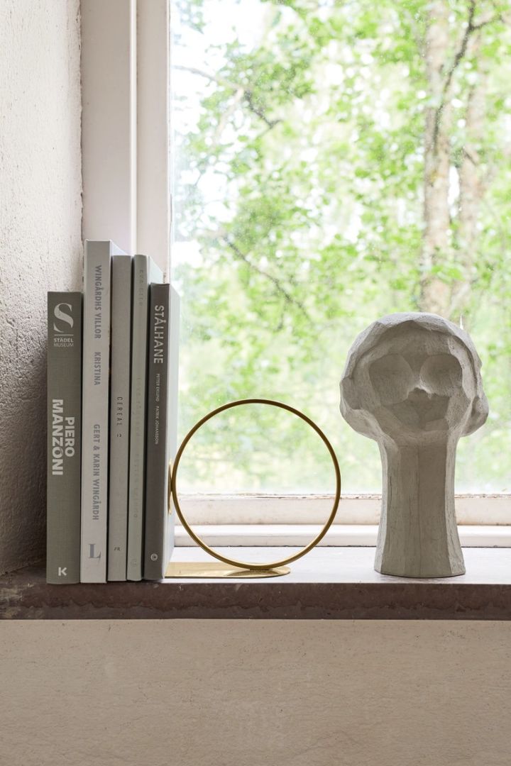 Stilleben i vinduet med bøker, bokstøtte i messing og skulptur i form av et kvinneansikt fra Cooee Design.