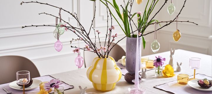 Lag et festlig påskebord i vårlige pasteller med påskeris i fargerike vaser som Curlie-vasen fra By On og Dorit-vasen fra Broste Copenhagen.