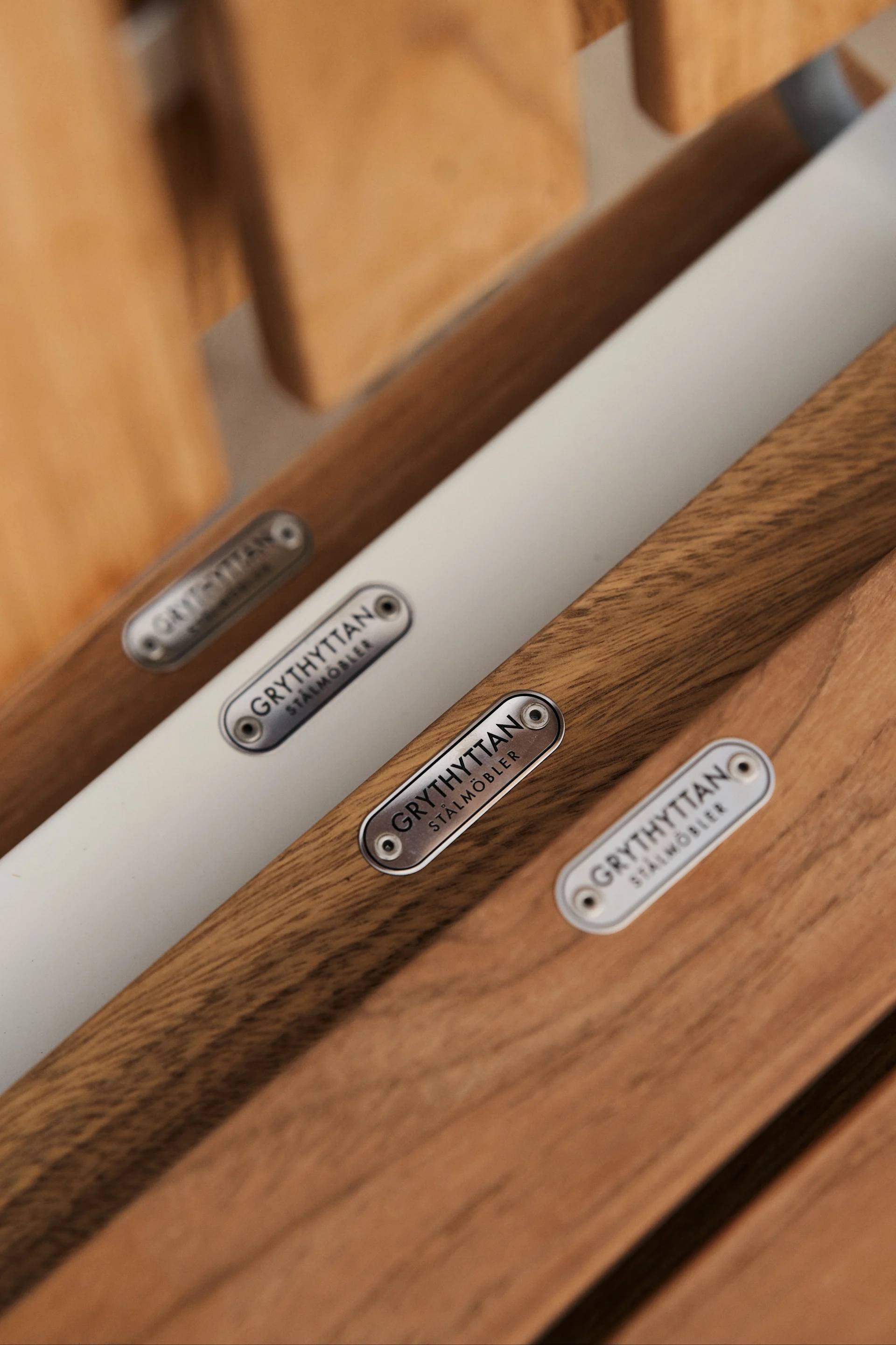 A2 stolen fra Grythyttan Stålmöbler er et ikon blant utemøbler i teak, her et detaljbilde av setet hvor logoen i galvanisert stål sitter som en vakker detalj.