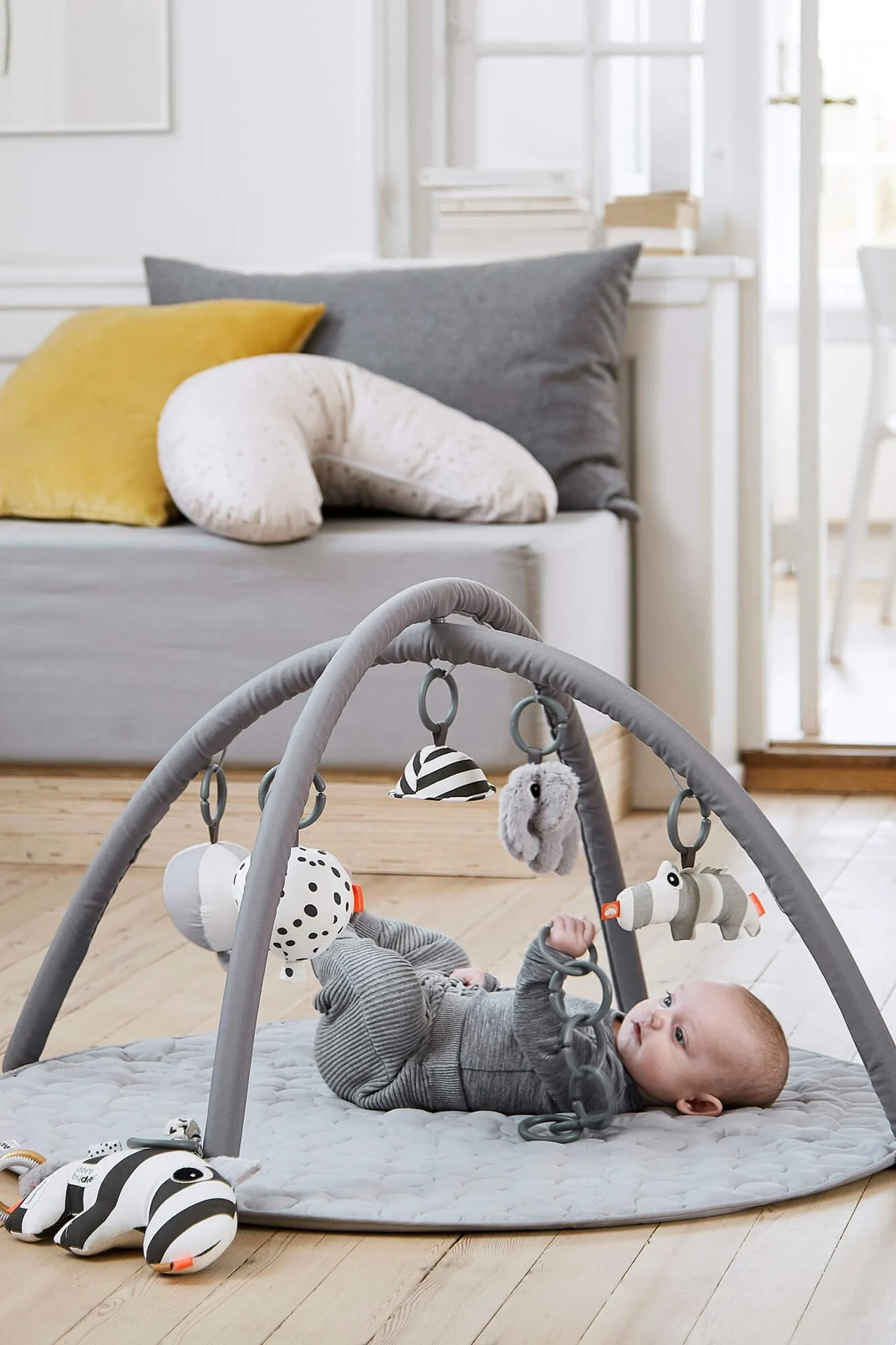 En smilende blekksprut-kosebamse ligger på en quiltet lekematte. Kosedyr er den perfekte gaveidéen til babyshower for den lille.