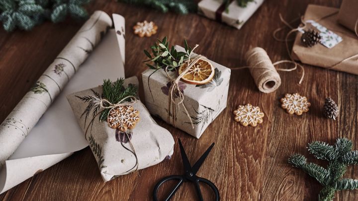 Julegavene venter på bordet, innpakket i blomstrende taper for en miljøvennlig gaveinnpakking til jul.