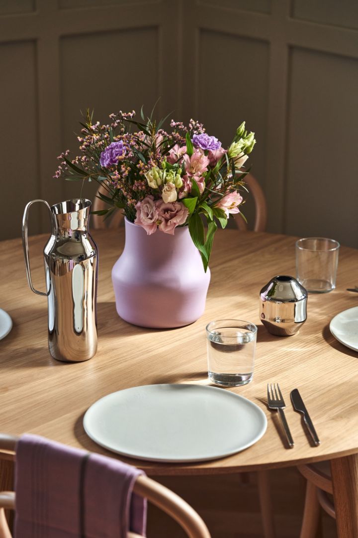 Lilla Dorotea-vasen på bordet med en kanne i rustfritt stål og minivase fra samme kolleksjon.