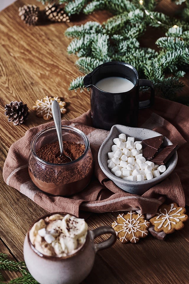 Adventskos med varm kakao med ingrediensene, som kakao, melk og minimarshmallows, står ved siden av i skåler.