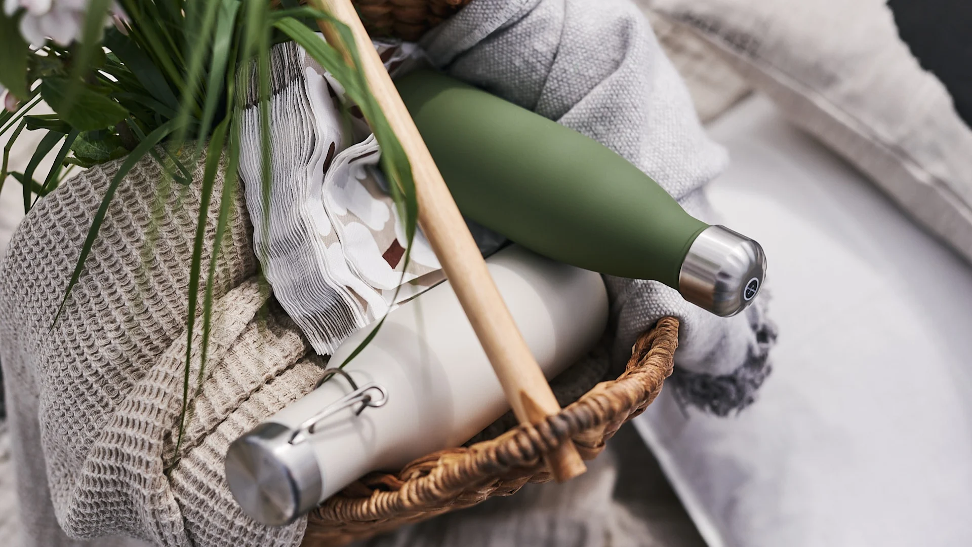En piknikkurv fylt med servietter, tepper og termosflasker klar til å ta med på piknik på stranden.