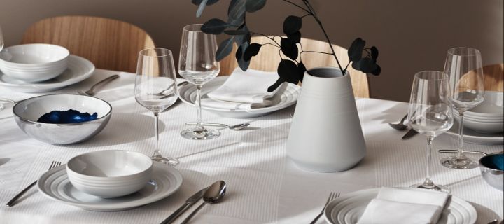 Vinglass på en hvit borddekking med NRJD-tallerkener og servise.