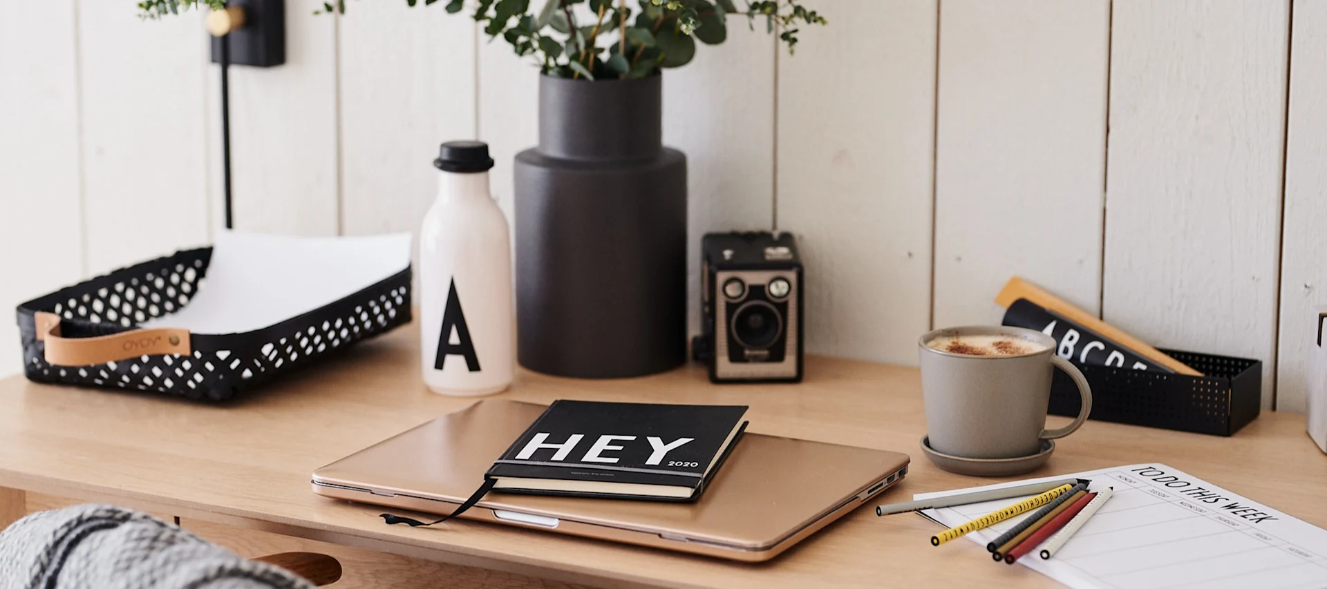Et lite hjemmekontor med Design Letter dagbok, ukeplanlegger og vannflaske.