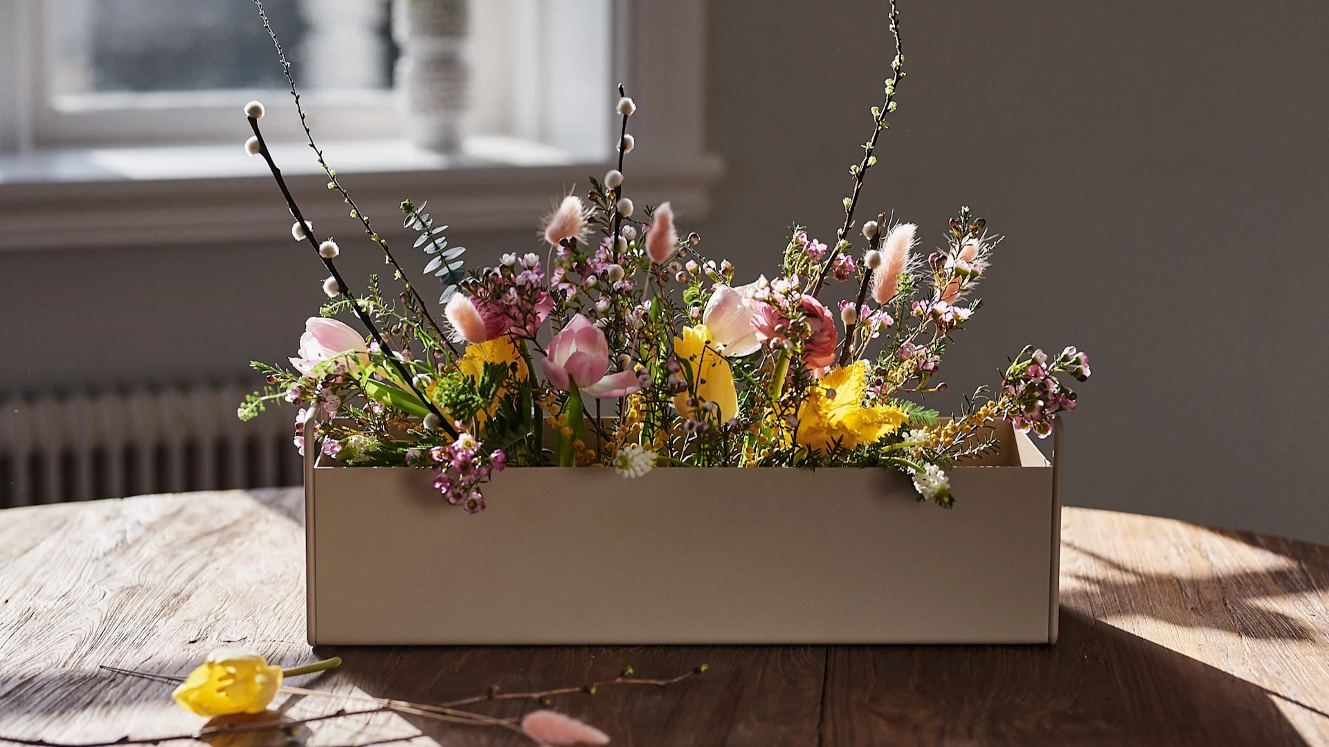 Liten beige Plant Box fra Ferm Living står på bordet med vårblomster i for interiørinspirasjon til våren.