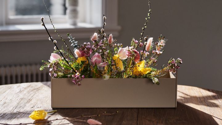 Liten beige Plant Box fra Ferm Living står på bordet med vårblomster i for interiørinspirasjon til våren.