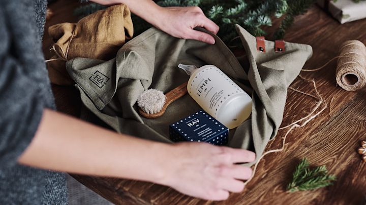 En gavepakke med såpe og børste pakkes inni kjøøkkenhåndklær for å gis bort som en zero waste-gave.