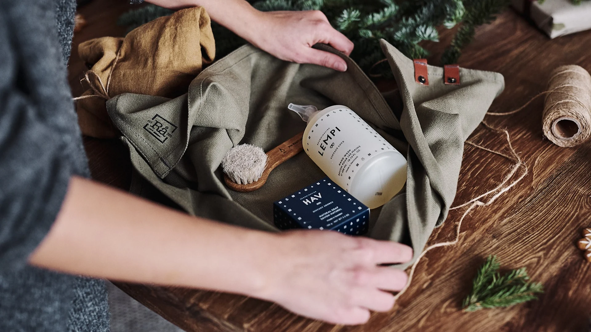 En gavepakke med såpe og børste pakkes inni kjøøkkenhåndklær for å gis bort som en zero waste-gave.