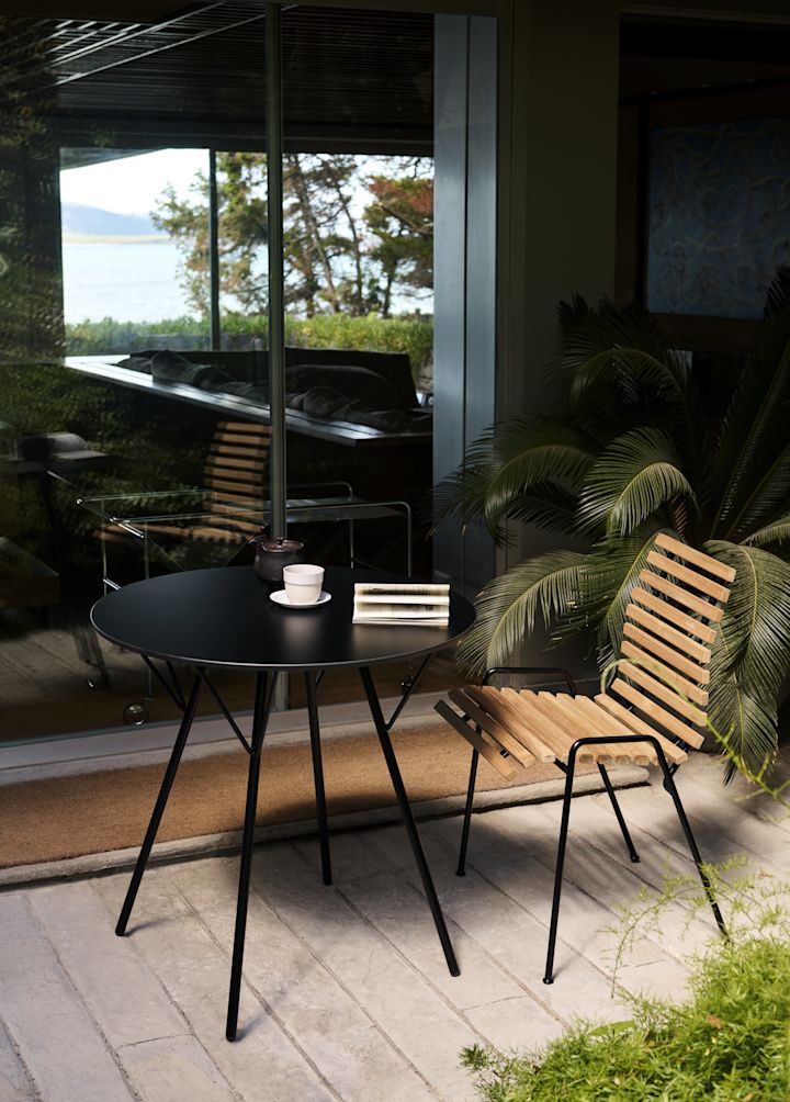 RFH RD4 Patio Side Chair fra &Tradition står på en uteplass sammen med et rundt bord.