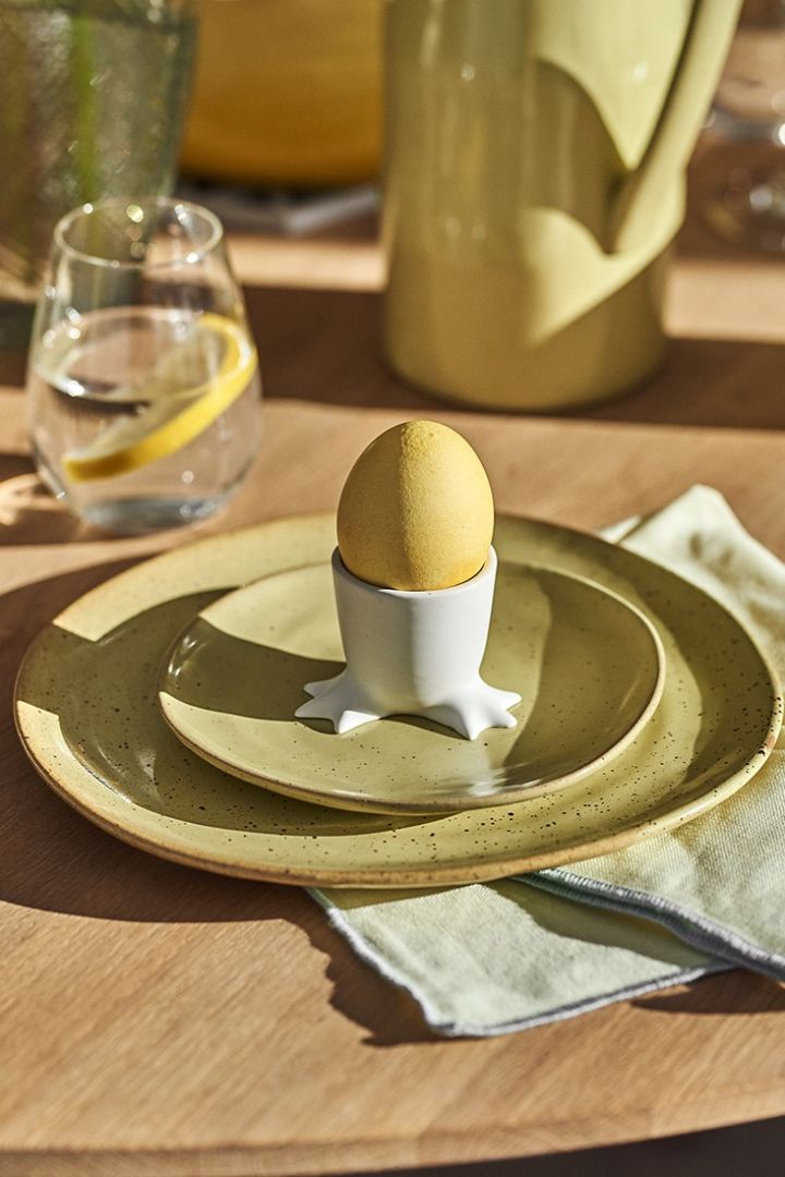 Et gult påskebord for familiens minste med gult servise og et lekent eggeglass fra DBKD.