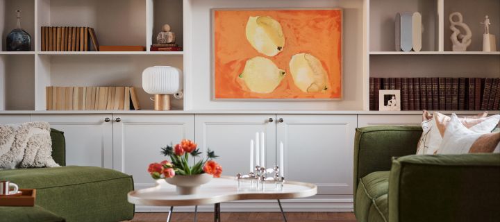 Interiørtrender 2024 - stue med grønn sofa, Swedese-bord, plakater med malt uttrykk og stilig bokhylle.