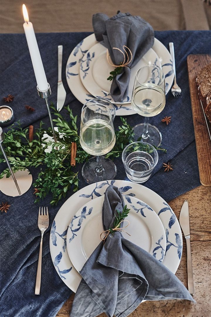 Romantisk borddekking på julaften med det blå og hvite serviset Havspil fra Nordic Nest Dining og Fuga-bestikk fra Gense.