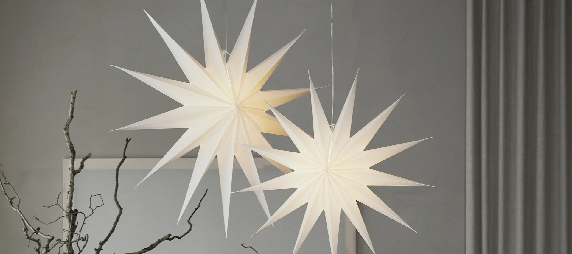 To røde adventsstjerner i papir fra Watt & Veke henger i stua.