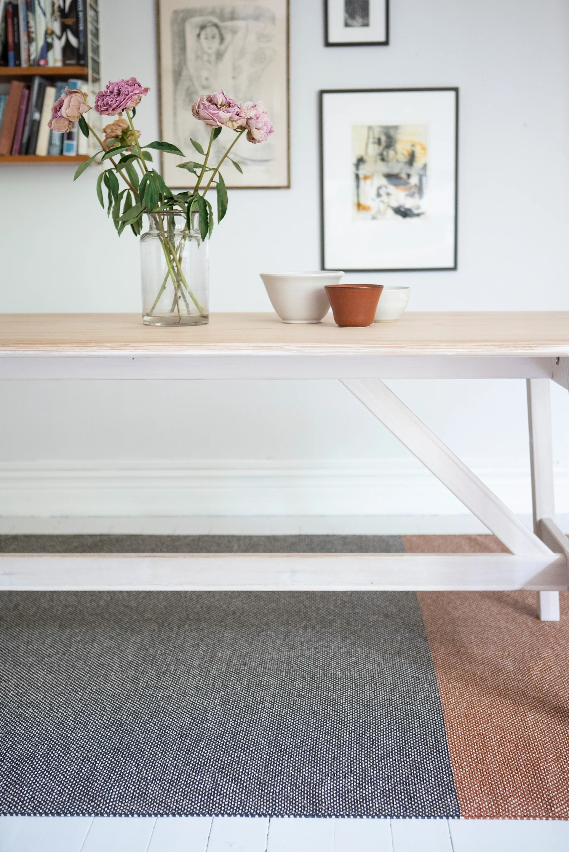 Gulvteppe til gangen: Moor-gulvteppet fra Brita Sweden ligger under et bord, med en vegg fylt av bilder i bakgrunnen.